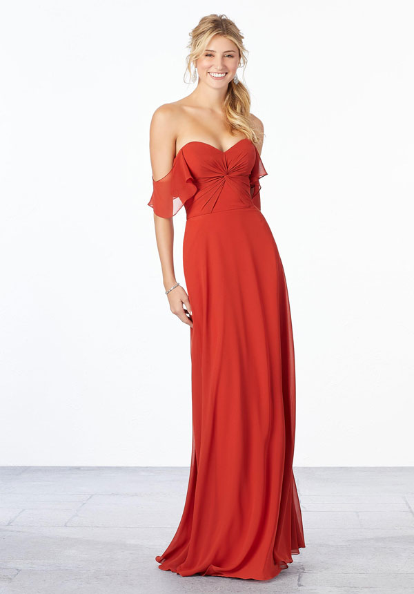 Young woman wearing cinnamon chiffon A-line bridesmaid dress with ruched bodice, sweetheart neckline, and off-the-shoulder flutter sleeves
